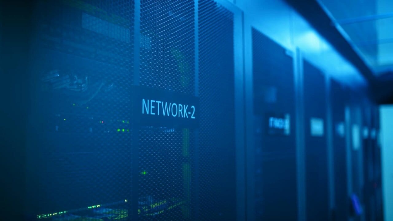 Row of server racks in a blue-lit datacentre corridor, marked NETWORK-2