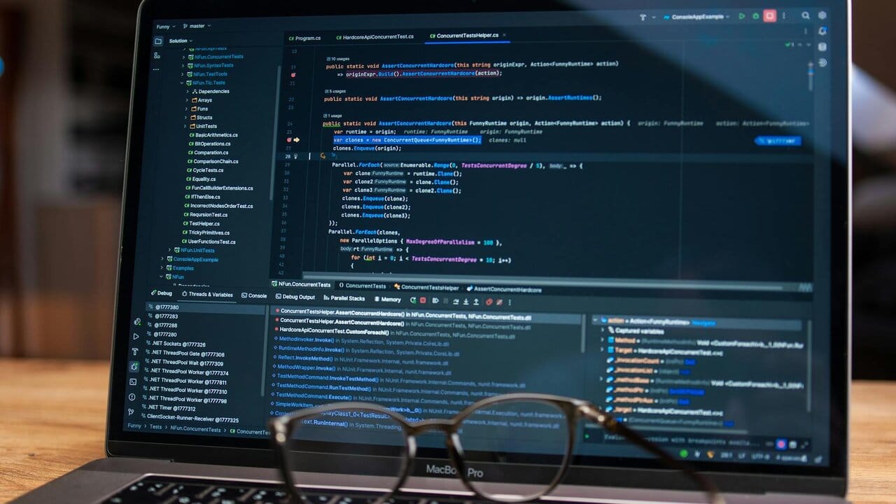 Close-up of a laptop screen displaying debugging software with source code in the background.