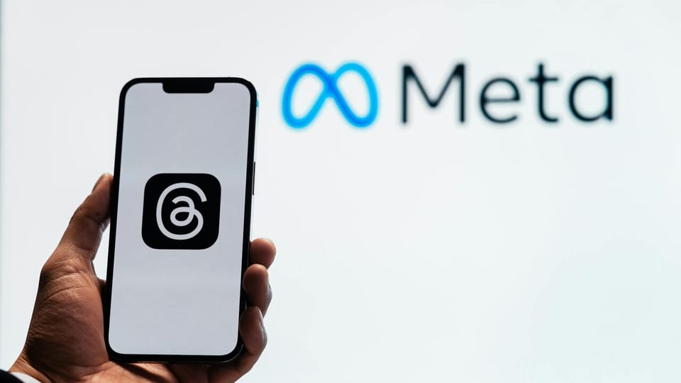 A smartphone displaying the Threads app, with the Meta Platforms logo visible in the background.